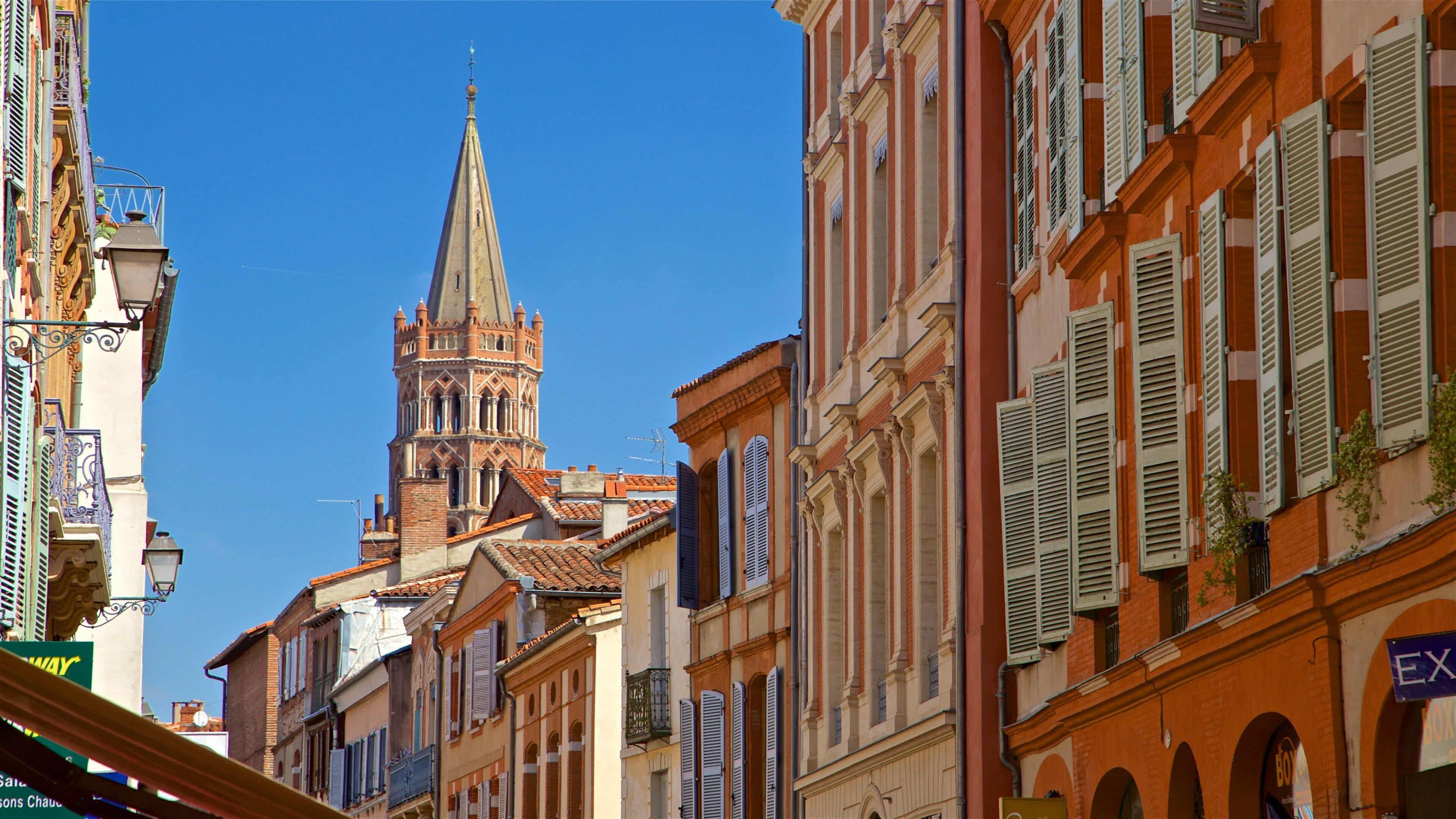 A historic street with a prominent church tower, colorful buildings, and a clear blue sky.