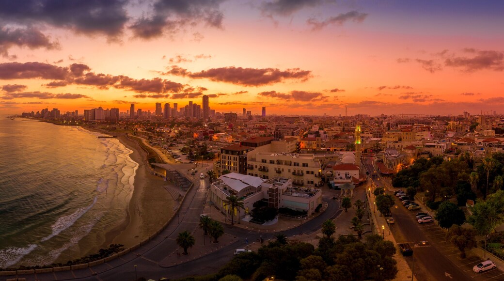 Paisagem costeira ao pôr do sol com um horizonte imponente, uma praia e uma estrada ao longo da costa.