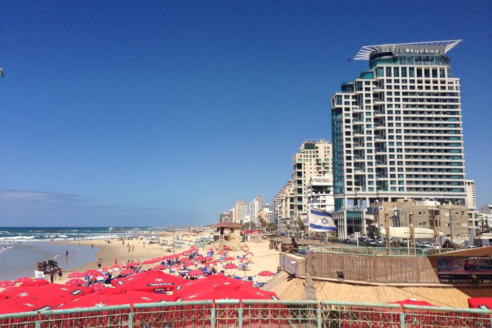 Una platja amb paraigües vermells i un hotel alt anomenat Royal Beach.