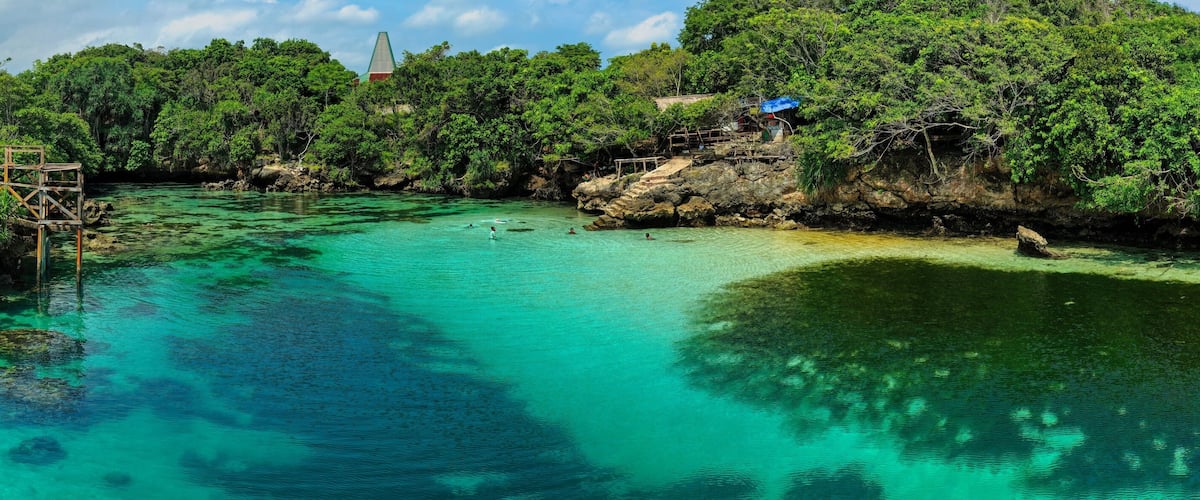 A clear turquoise river surrounded by lush greenery and rocky outcrops.