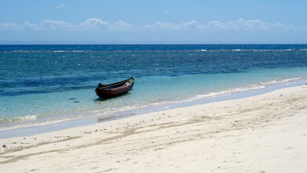 Un bateau sur une plage de sable, avec une eau dâun bleu limpide et une mer calme.
