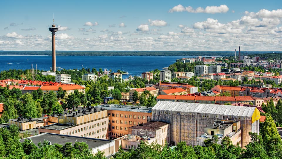 A cityscape with a prominent tower, a large body of water, and a mix of residential and industrial buildings.