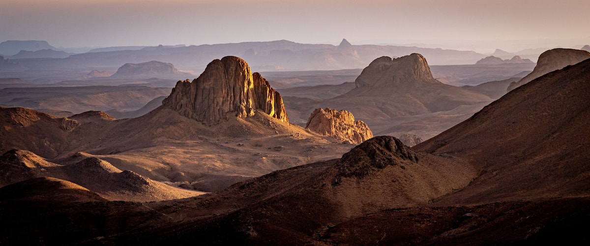 A desert landscape with prominent rock formations and distant mountains.