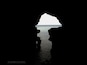 A silhouette of a cave entrance with a reflection of the sky and water.