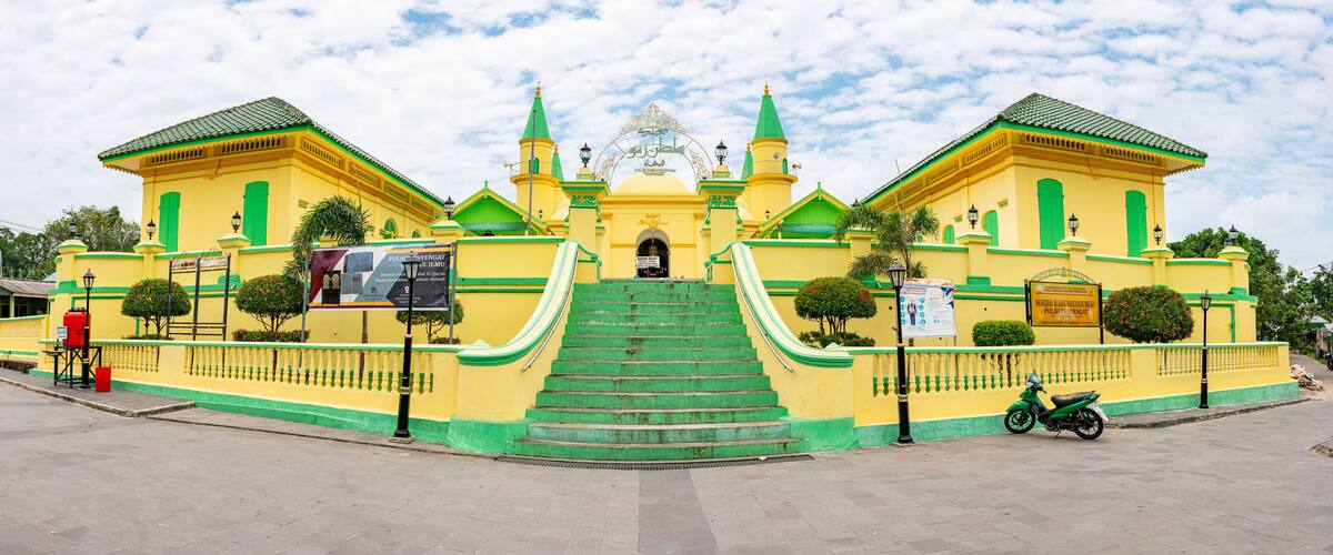 A large yellow and green building with a central dome and two green towers.