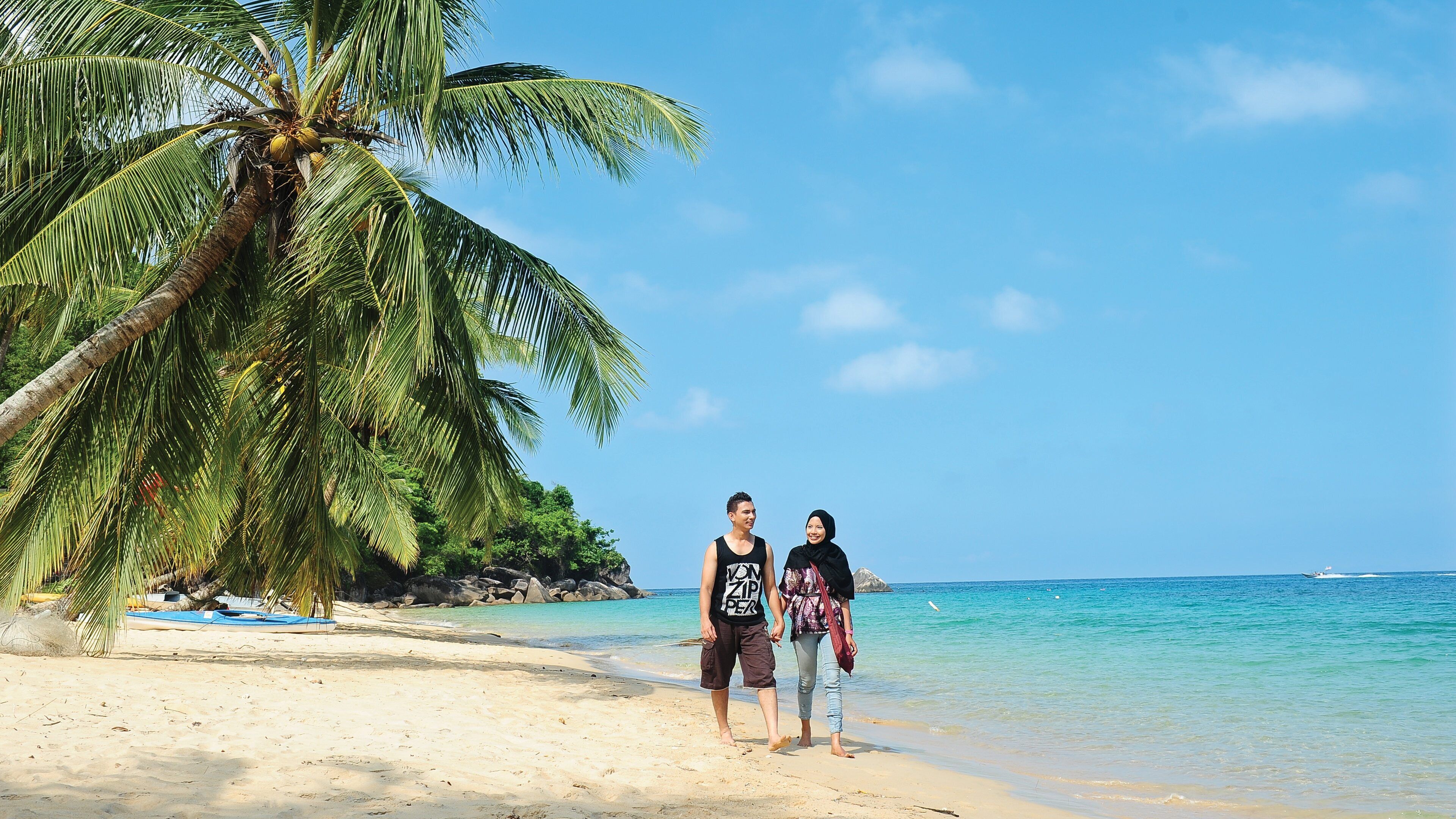 A beach with palm trees and clear blue water.