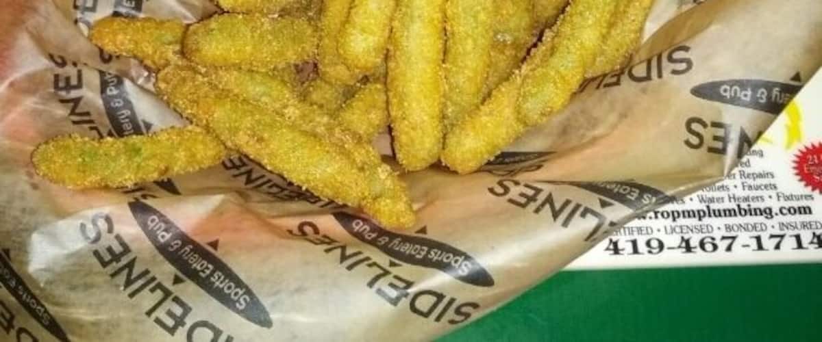 A basket of golden-brown fried food items, likely chicken tenders, accompanied by a small bowl of dipping sauce.