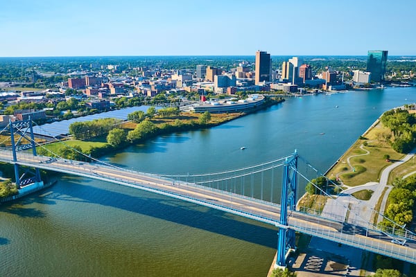 A river with a bridge, a city skyline, and a large building with a unique shape.