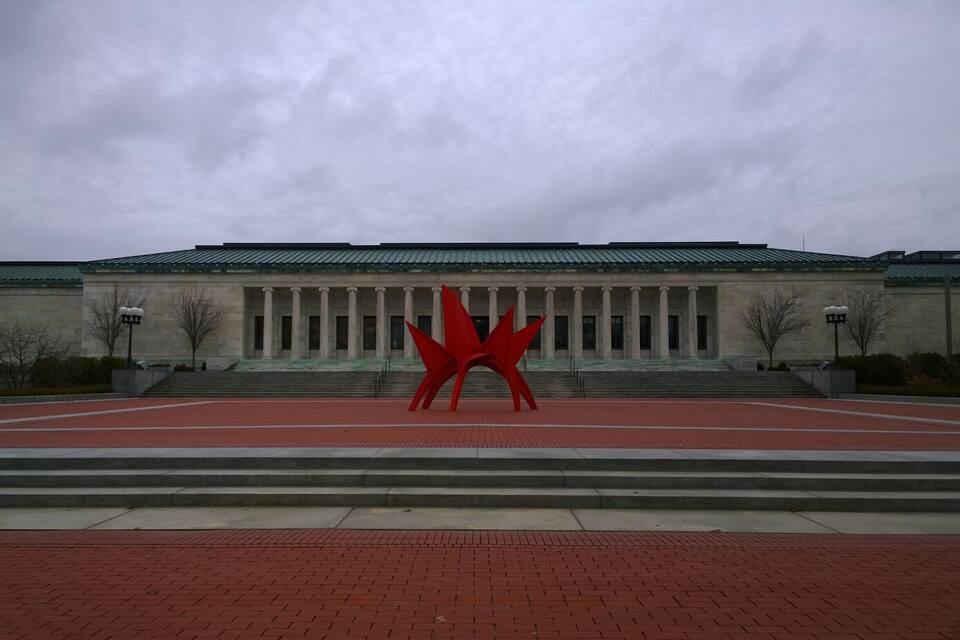 Un edificio con una escultura roja en su fachada.