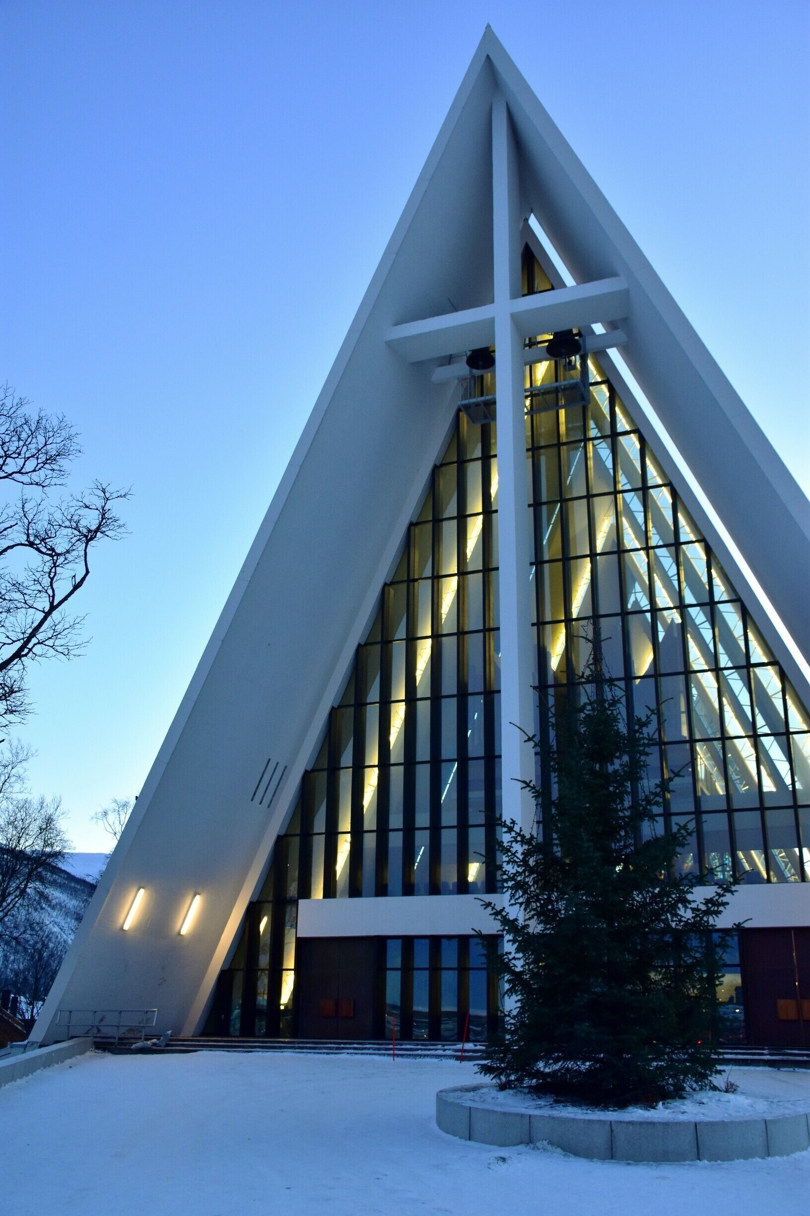 A modern building with a triangular design, large windows, and a snow-covered ground.