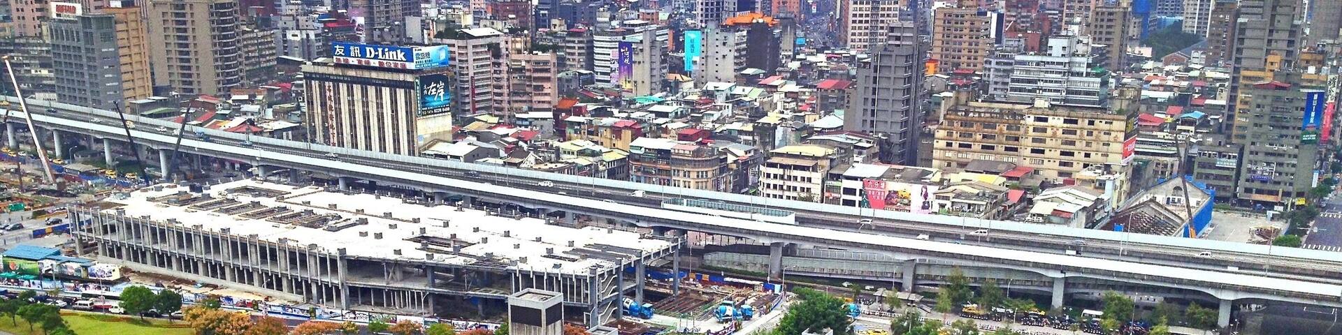 A cityscape with dense high-rise buildings, a large stadium, and a busy intersection with yellow taxis.