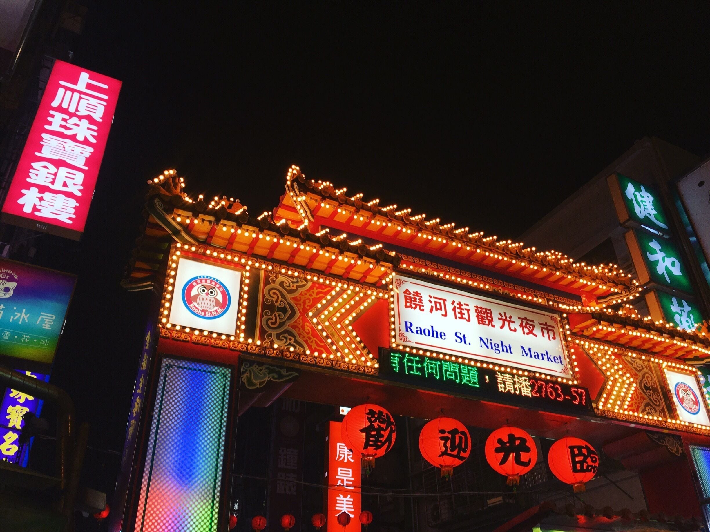 A brightly lit traditional Chinese building with ornate decorations and illuminated signs.
