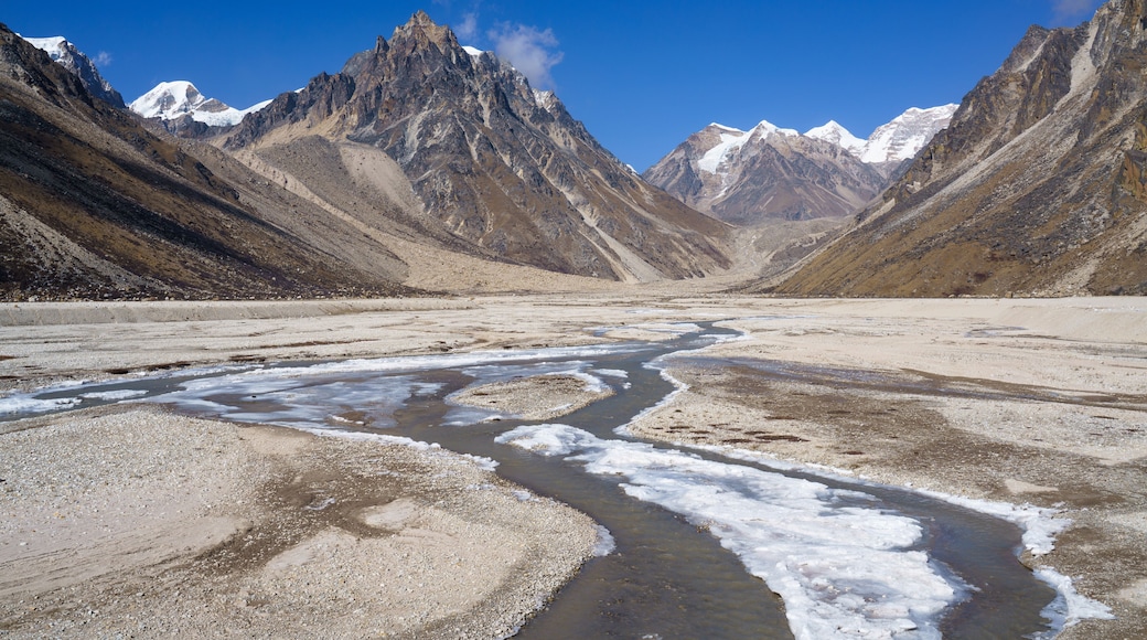 A high plateau with a frozen mountain river during the Kanchenjunga Base Camp Trek in Nepal. The trek offers stunning views of the third-highest mountain in the world and its surrounding peaks.
