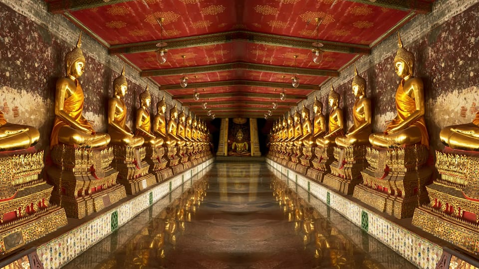 A corridor lined with golden Buddha statues and ornate thrones.