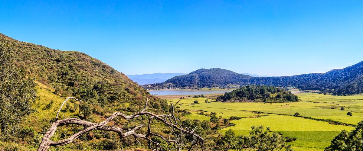 A valley with green fields, a lake, and mountains.