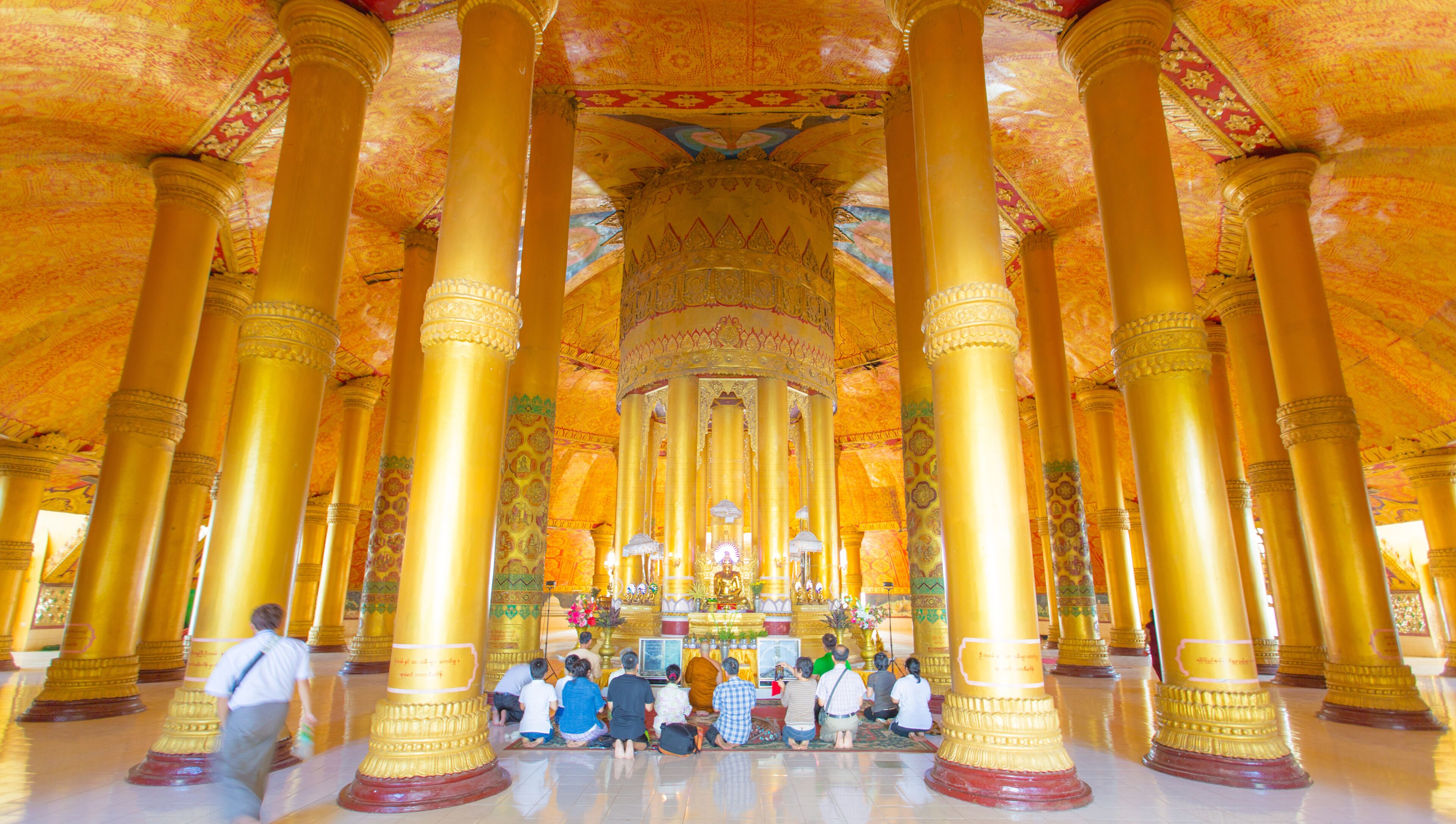 A temple interior with golden columns and intricate ceiling designs.