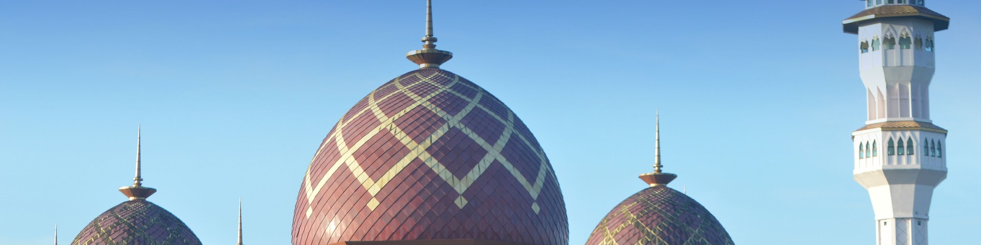 Una mezquita con tres cúpulas grandes y un minarete.
