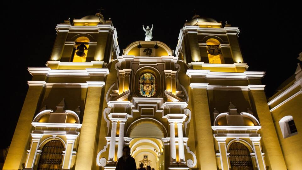 A grand cathedral with two bell towers, a central dome, and a statue on top.