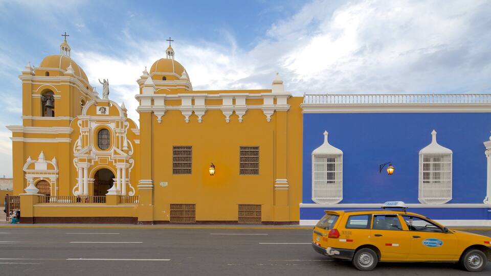 A yellow church with white domes and a blue building with white window frames.