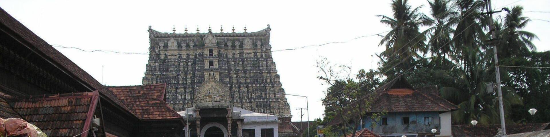 A street with a large temple in the background, a parked truck, and people walking.