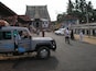 Une rue avec un grand temple en arrière-plan, un camion garé et des gens qui marchent.