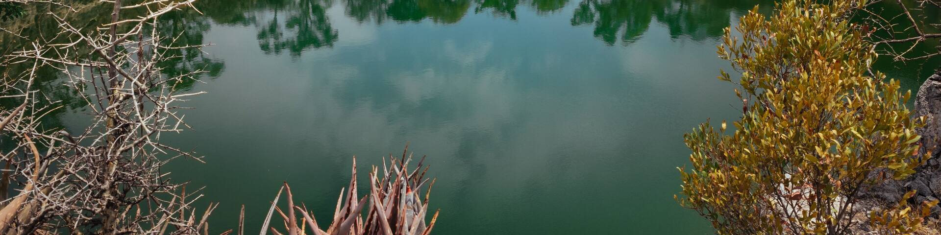 A calm lake surrounded by rocky terrain and sparse vegetation.