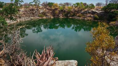 Um lago tranquilo rodeado por terreno rochoso e vegetação escassa.
