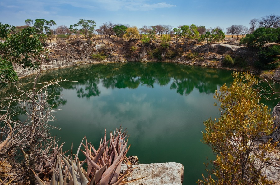A calm lake surrounded by rocky terrain and sparse vegetation.