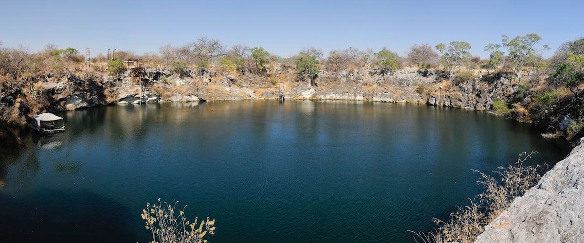 A calm lake surrounded by rocky terrain and sparse vegetation.