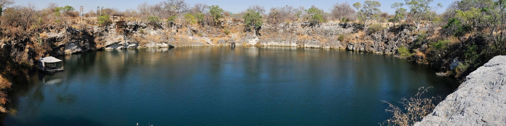 A calm lake surrounded by rocky terrain and sparse vegetation.