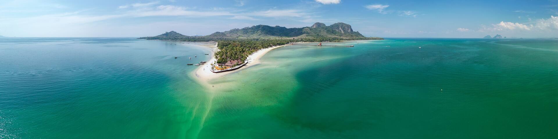A tropical island with clear turquoise waters, a sandy beach, and a prominent mountain.