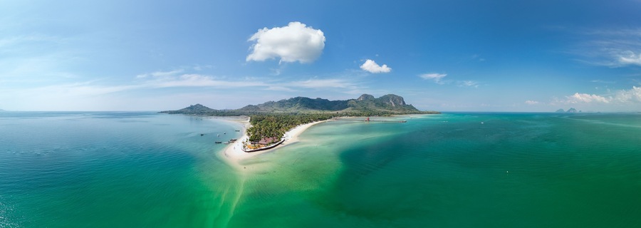 Eine tropische Insel mit klarem türkisblauem Wasser, einem Sandstrand und einem markanten Berg.