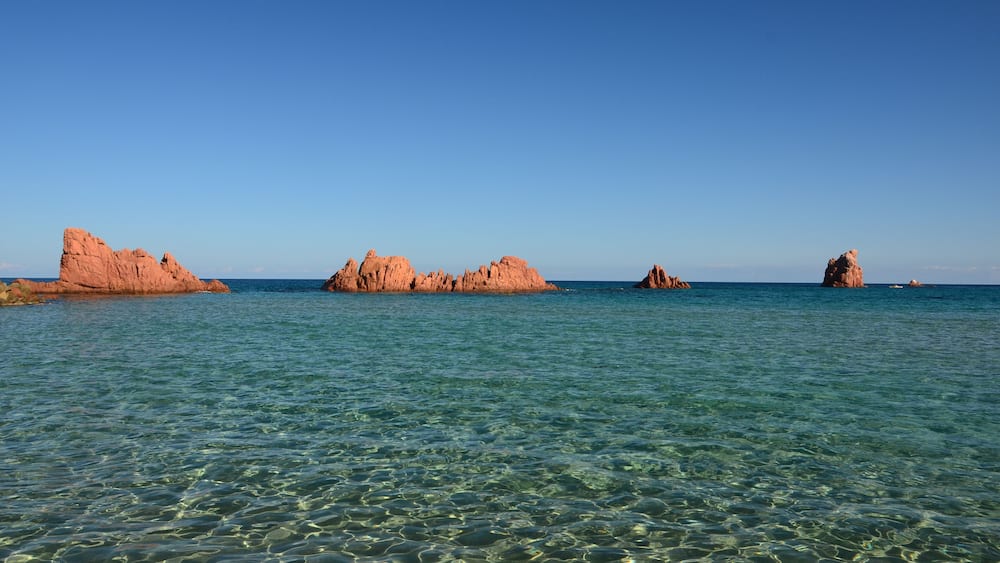 Une eau turquoise et limpide, des formations rocheuses et un ciel bleu azur.