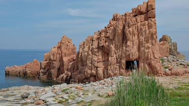 Un paisaje costero rocoso con una formación rocosa destacada y la entrada de una cueva.