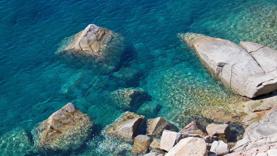 Clear blue water with visible rocks and a rocky shoreline.