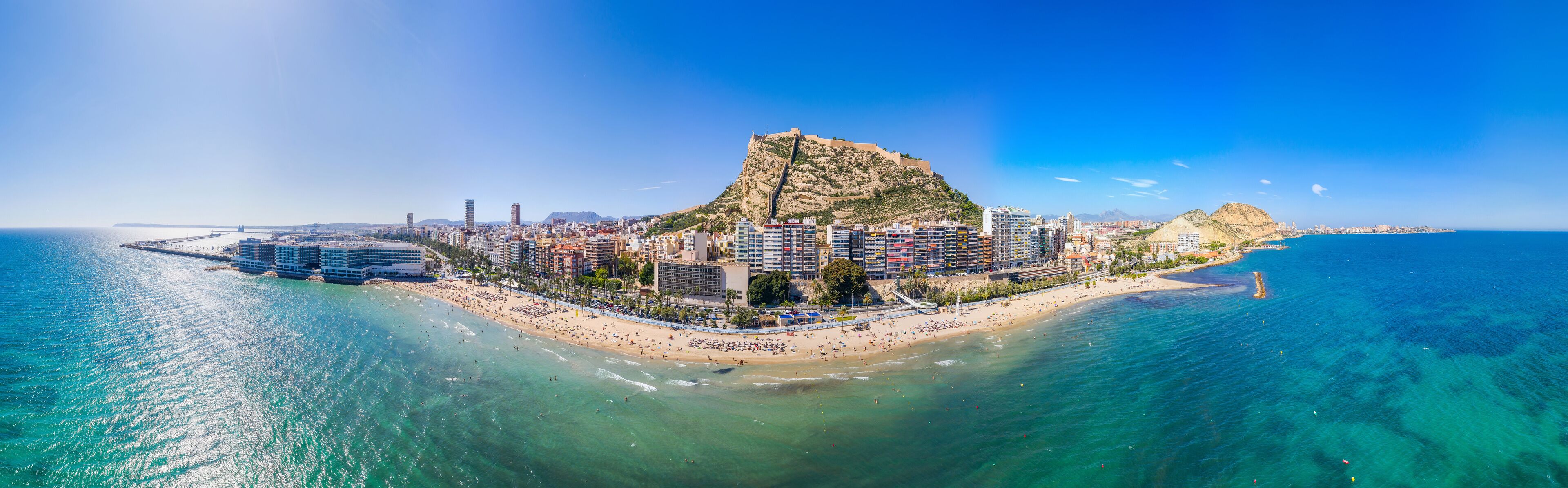 A coastal city with a prominent hill, a beach, and a marina.