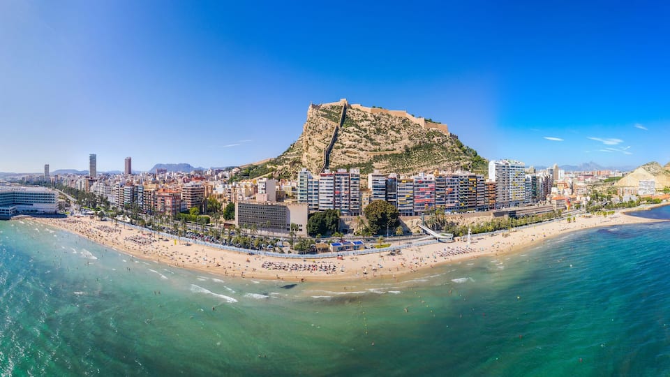 A coastal city with a prominent hill, a beach, and a marina.