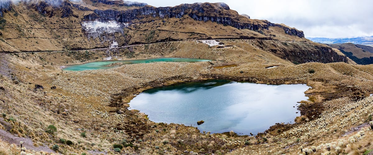 A mountainous landscape with a small lake surrounded by rocky terrain and sparse vegetation.