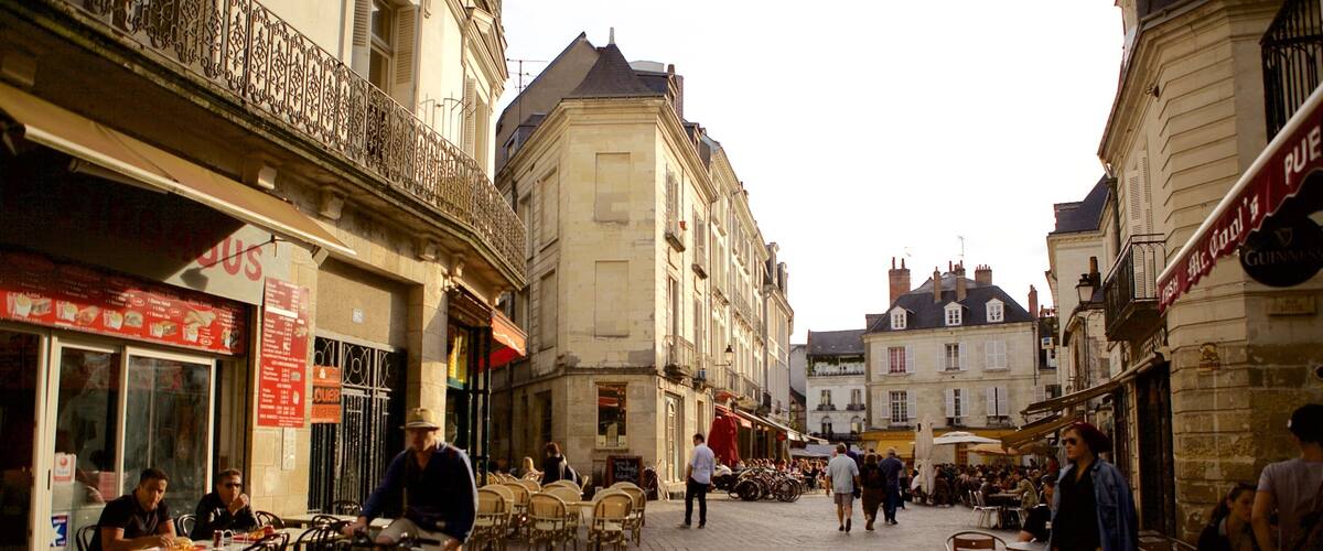A cobblestone street with outdoor cafes, bicycles, and pedestrians.