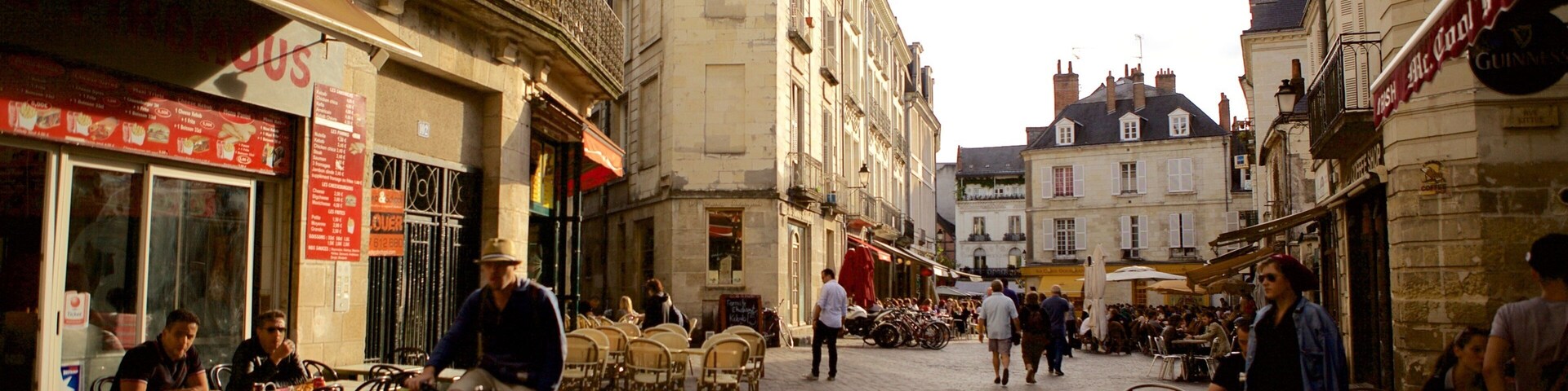 A cobblestone street with outdoor cafes, bicycles, and pedestrians.
