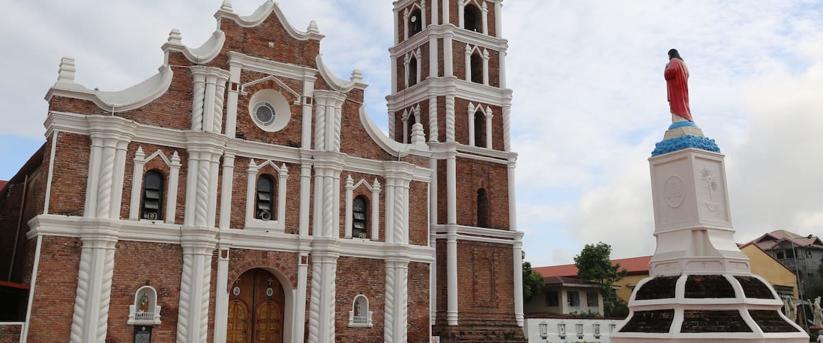 A historic church with a bell tower and a statue of a religious figure.