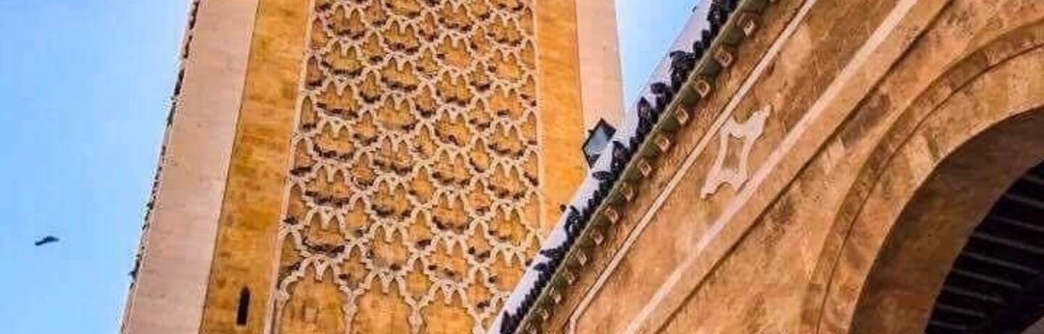Uma torre alta com padrões geométricos complexos e uma série de arcos.