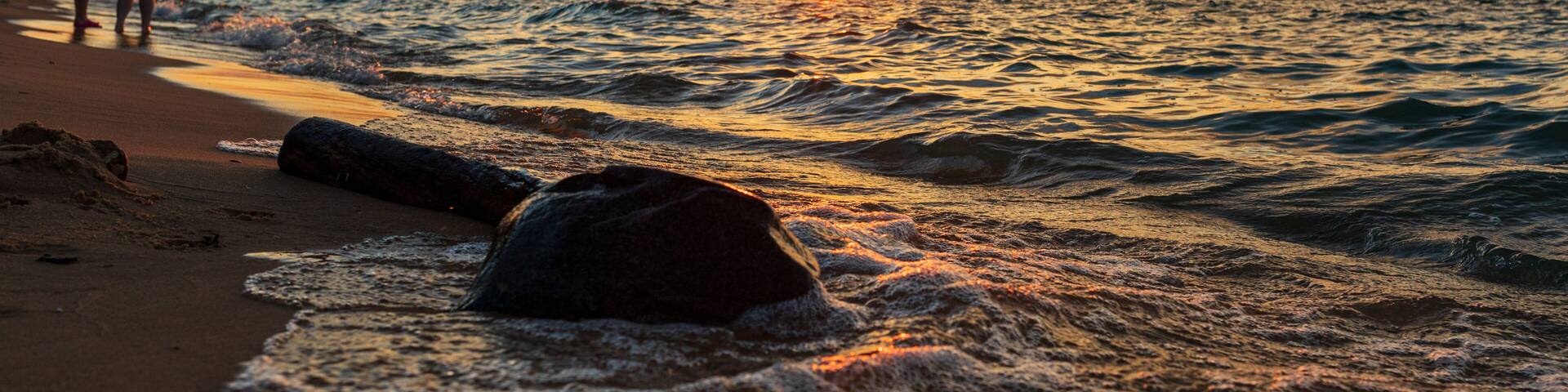 People watching sunset along beach on Lake Michigan.