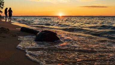 People watching sunset along beach on Lake Michigan.
