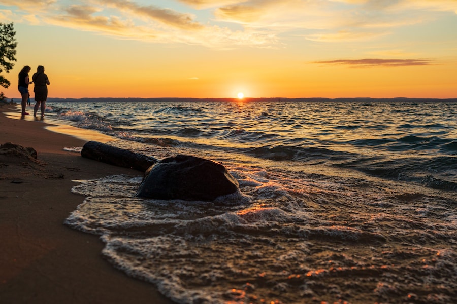 People watching sunset along beach on Lake Michigan.