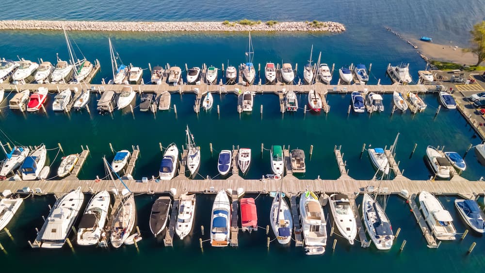Eine Luftaufnahme eines Yachthafens mit zahlreichen Booten an Holzstegen.