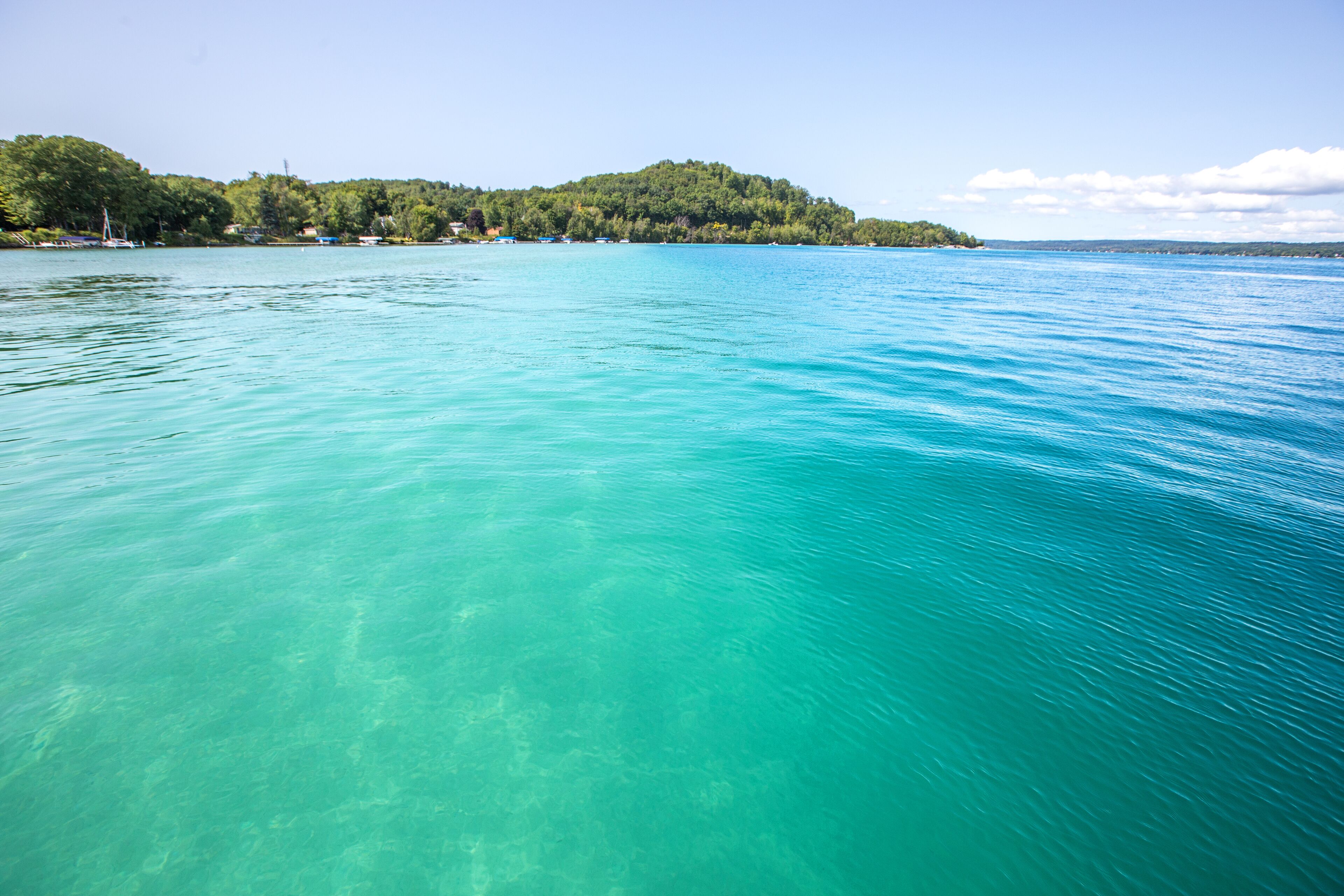 A clear turquoise lake with a forested island in the background.