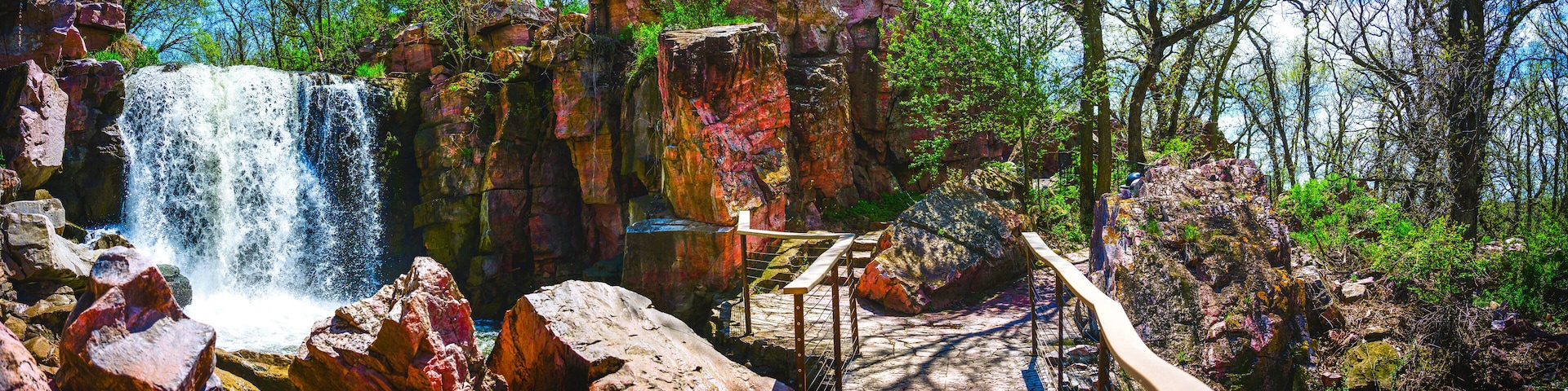 A waterfall, rocky terrain, and a wooden bridge.