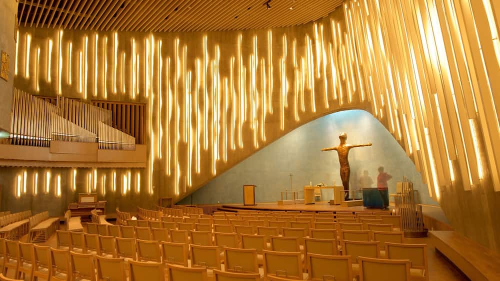 A church interior with a wooden organ, rows of chairs, and a crucifix.