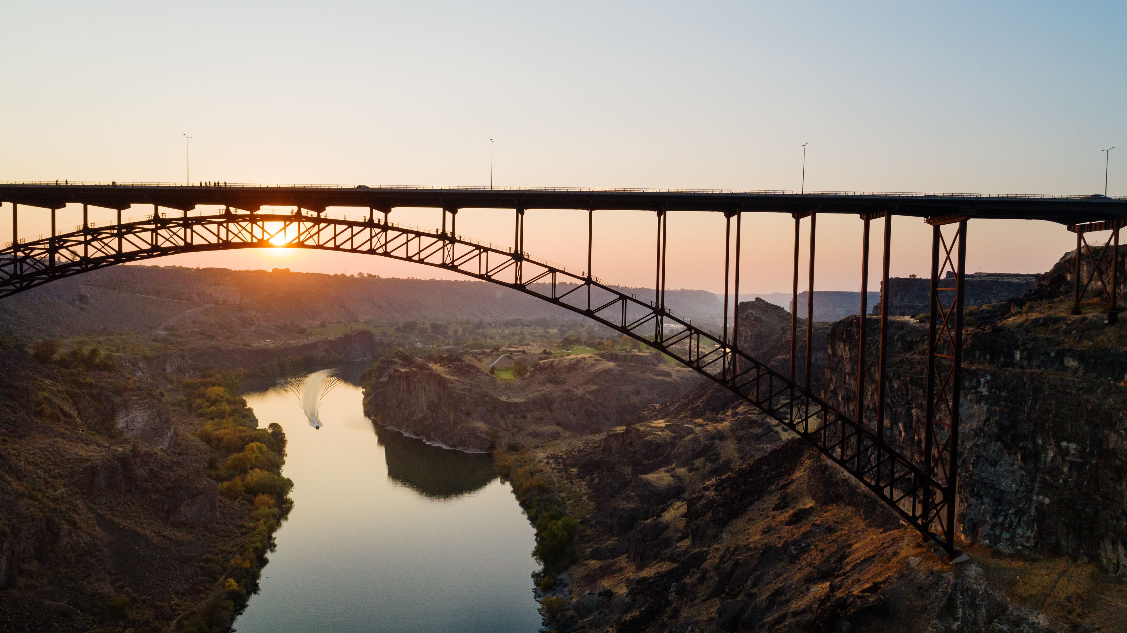 A bridge spans a river with a sunset in the background